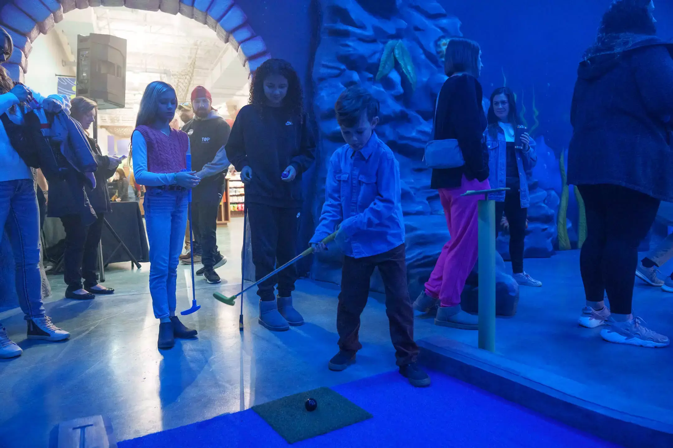 son playing golf on the indoor course